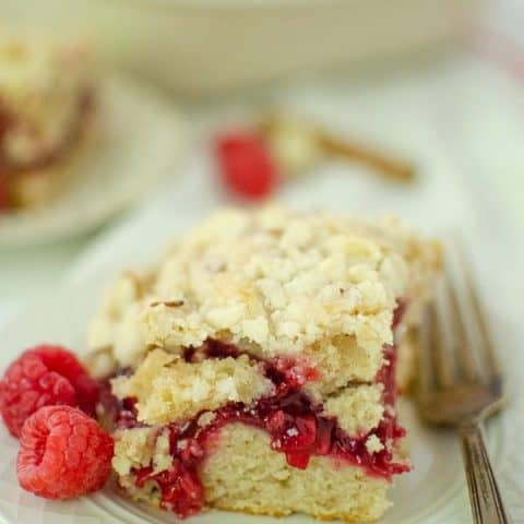 Raspberry Coffee Cake with crumb topping on small plate with fork and raspberries