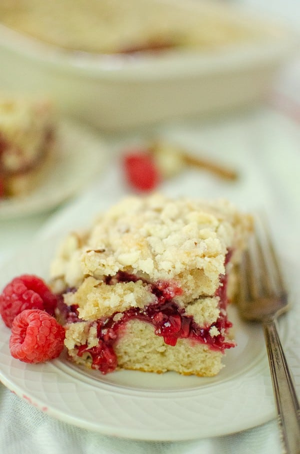 Raspberry Coffee Cake with crumb topping on small plate with fork and raspberries