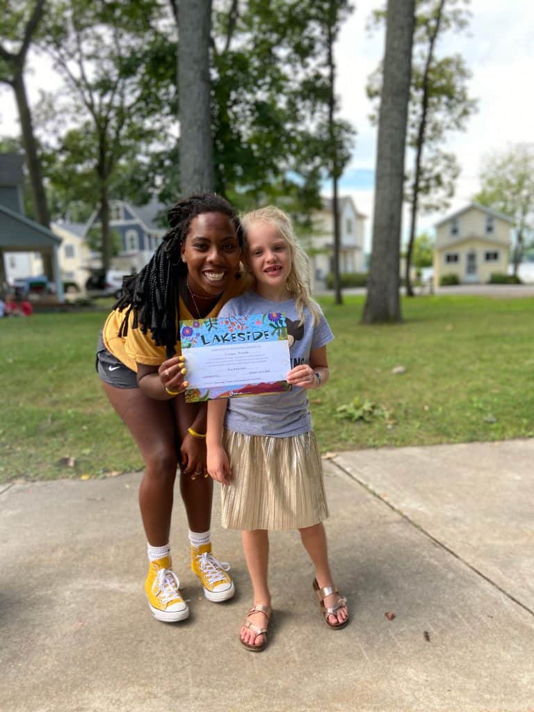 young girl stands with her camp counselor