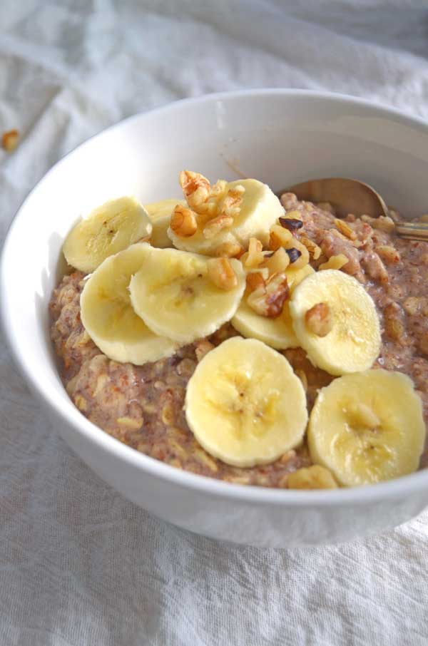 Banana Bread Oatmeal in white bowl topped with bananas and walnuts