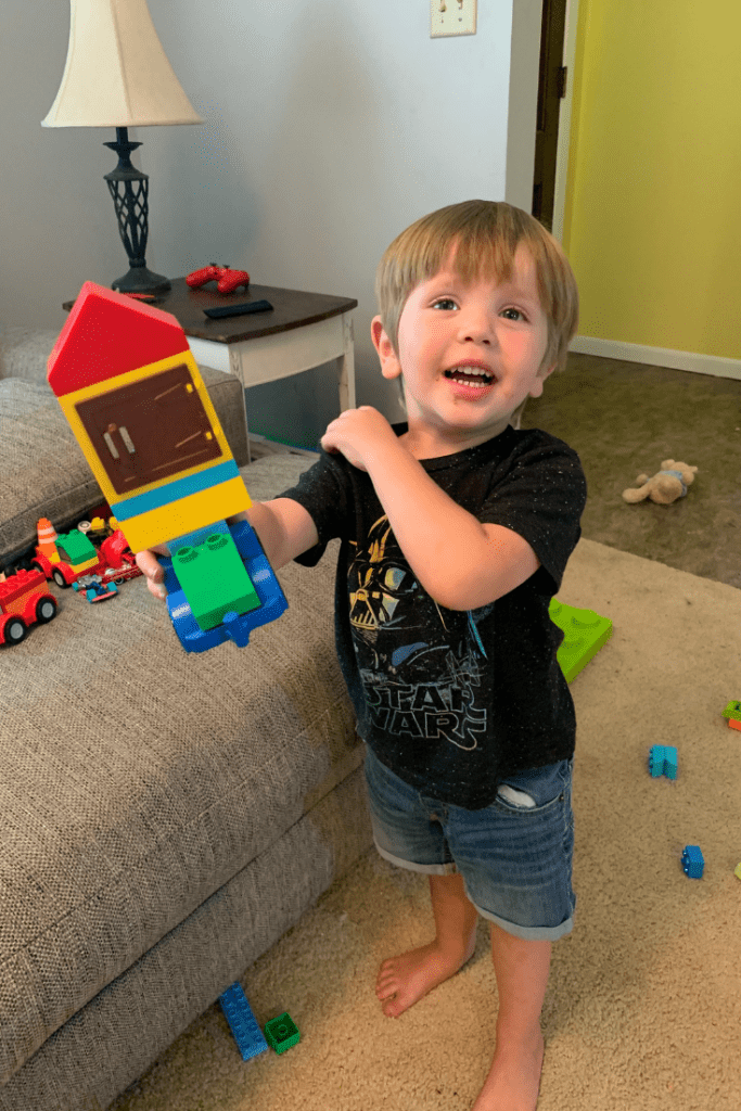 toddler holds up duplo lego build