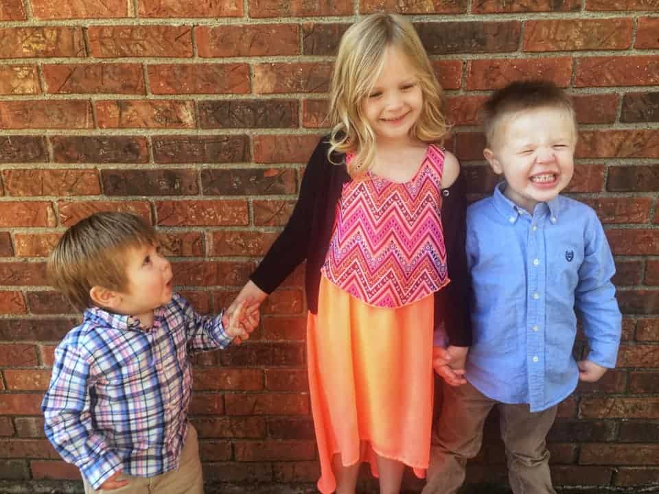 Three cute kids dressed in their Easter finest against a brick background
