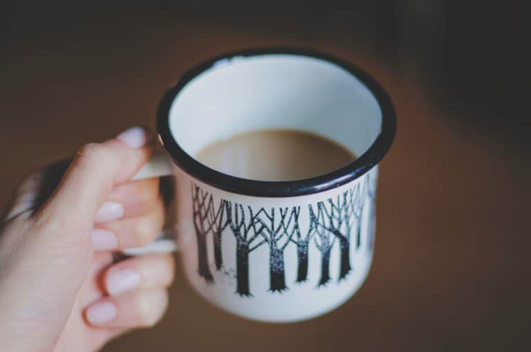coffee cup with trees in hand with painted nails