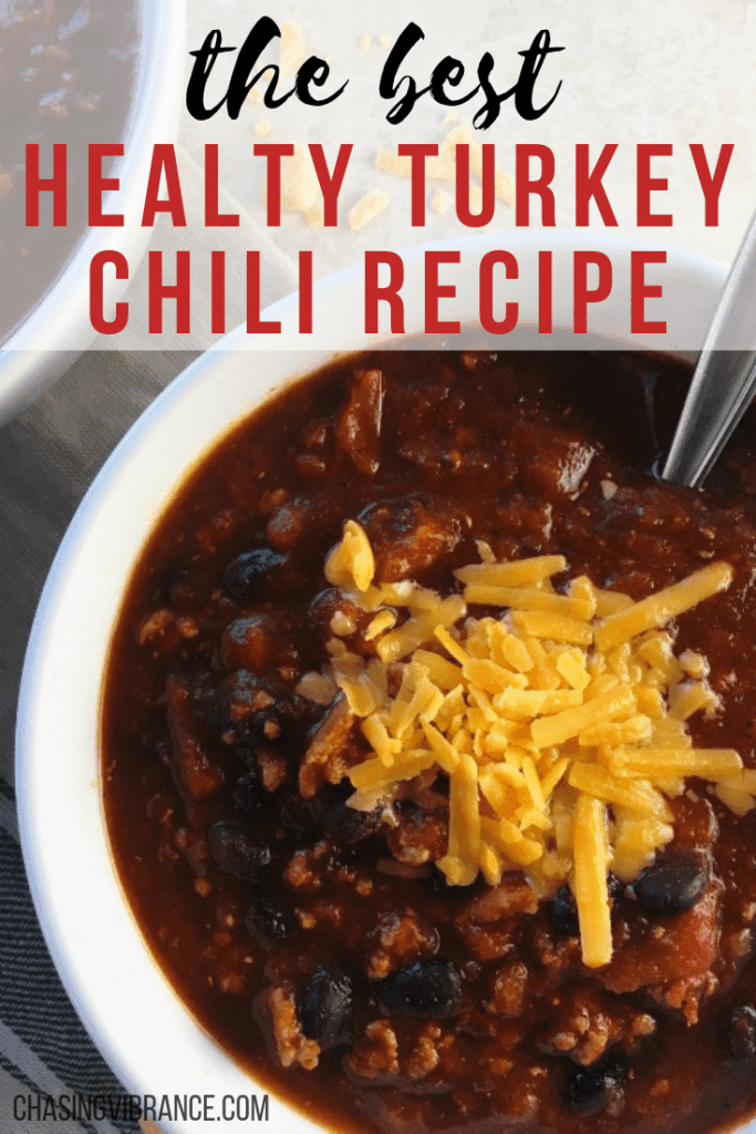 Turkey chili in a white bowl topped with cheddar cheese