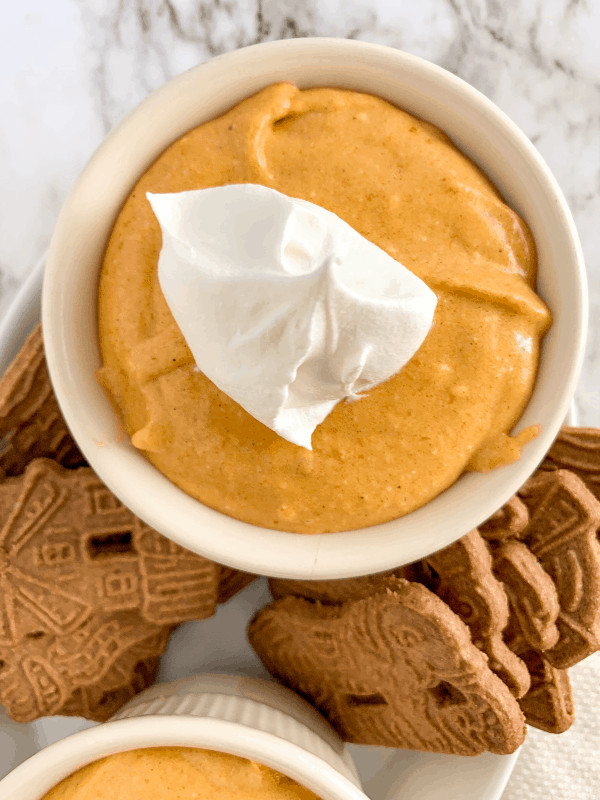 Small bowl of cheesecake pumpkin dip with whipped cream and gingersnaps