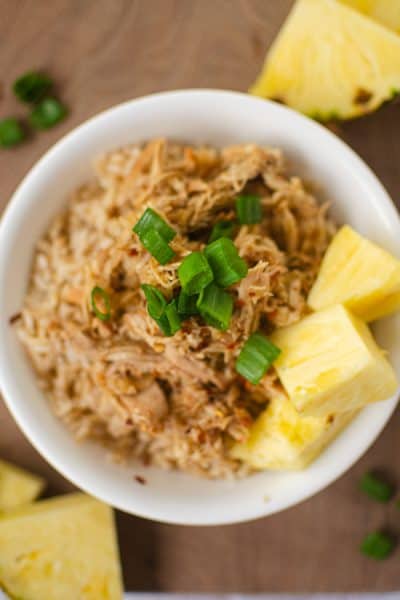 overhead photo of white bowl filled with rice, hawaiian chicken, pineapple and green onion