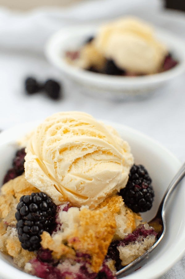Blackberry cobbler in white bowl with ice cream