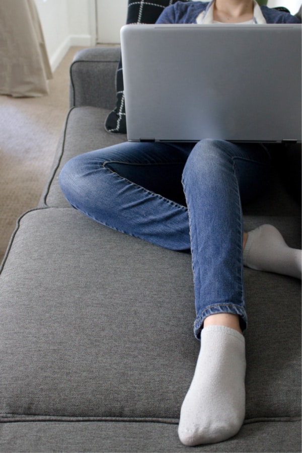 woman searching computer sitting on a gray couch