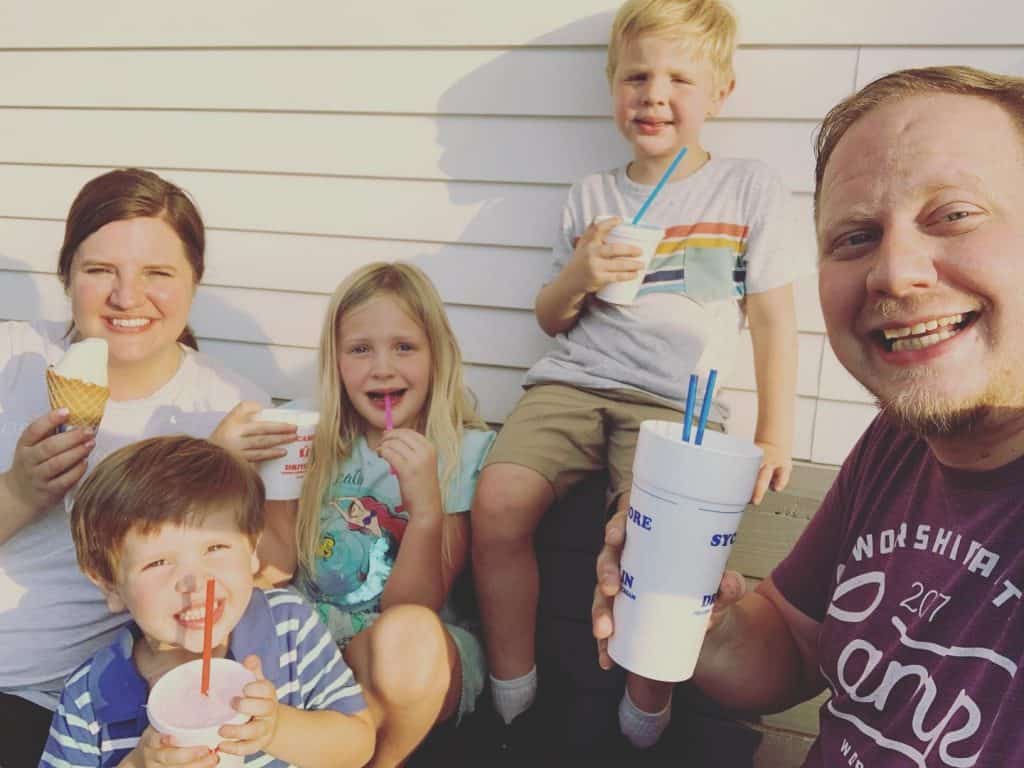 mom and dad with three kids eating ice cream outdoors