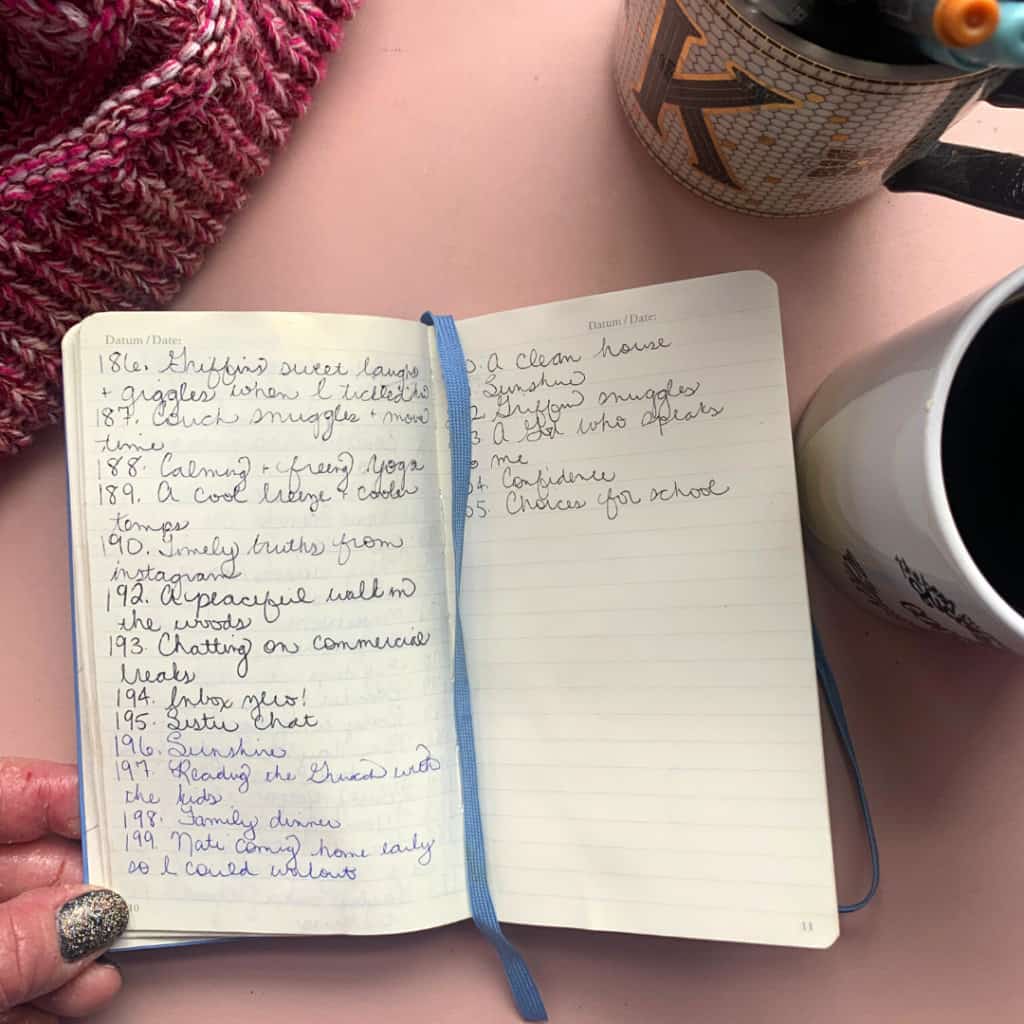 small gratitude journal open to a page with cup of coffee and beanie in background