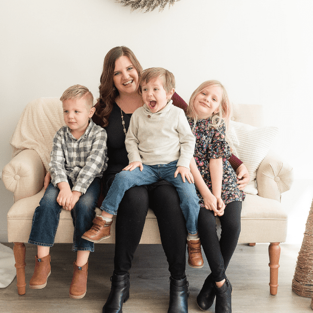 woman holds three boisterous kids on her lap on small couch