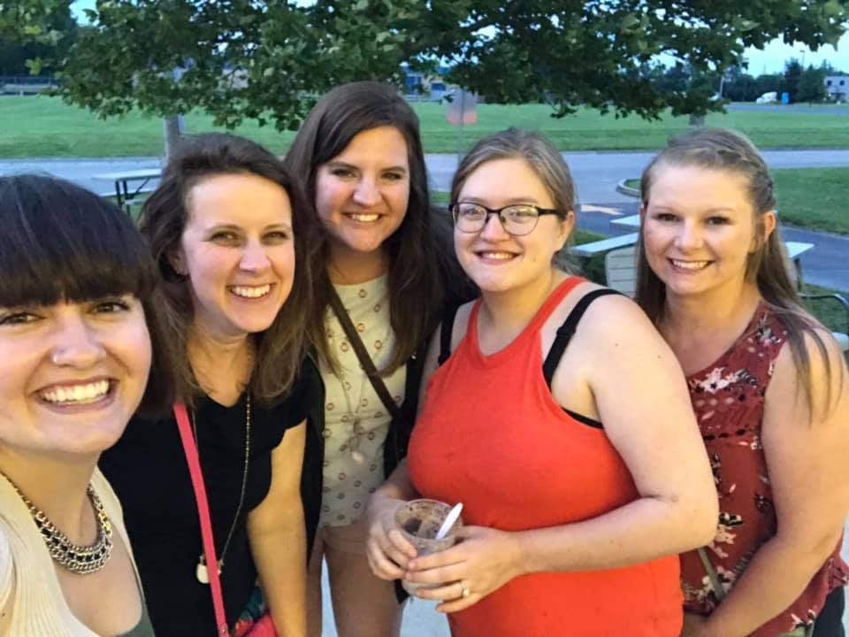 Group of young moms hang out after Bible study with big smile on their faces. 