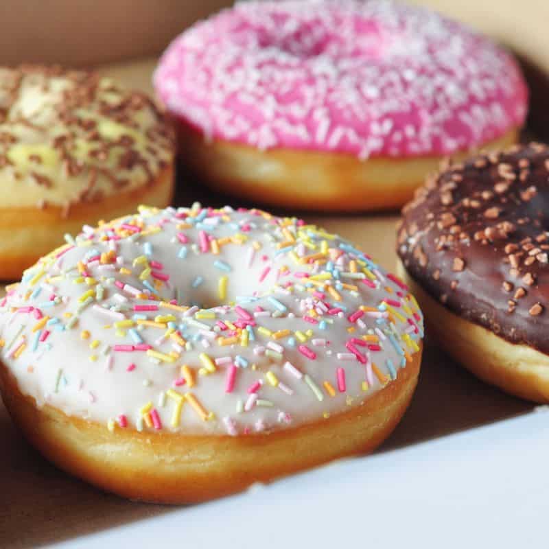 box of pastel colored doughnuts with sprinkles in a white box