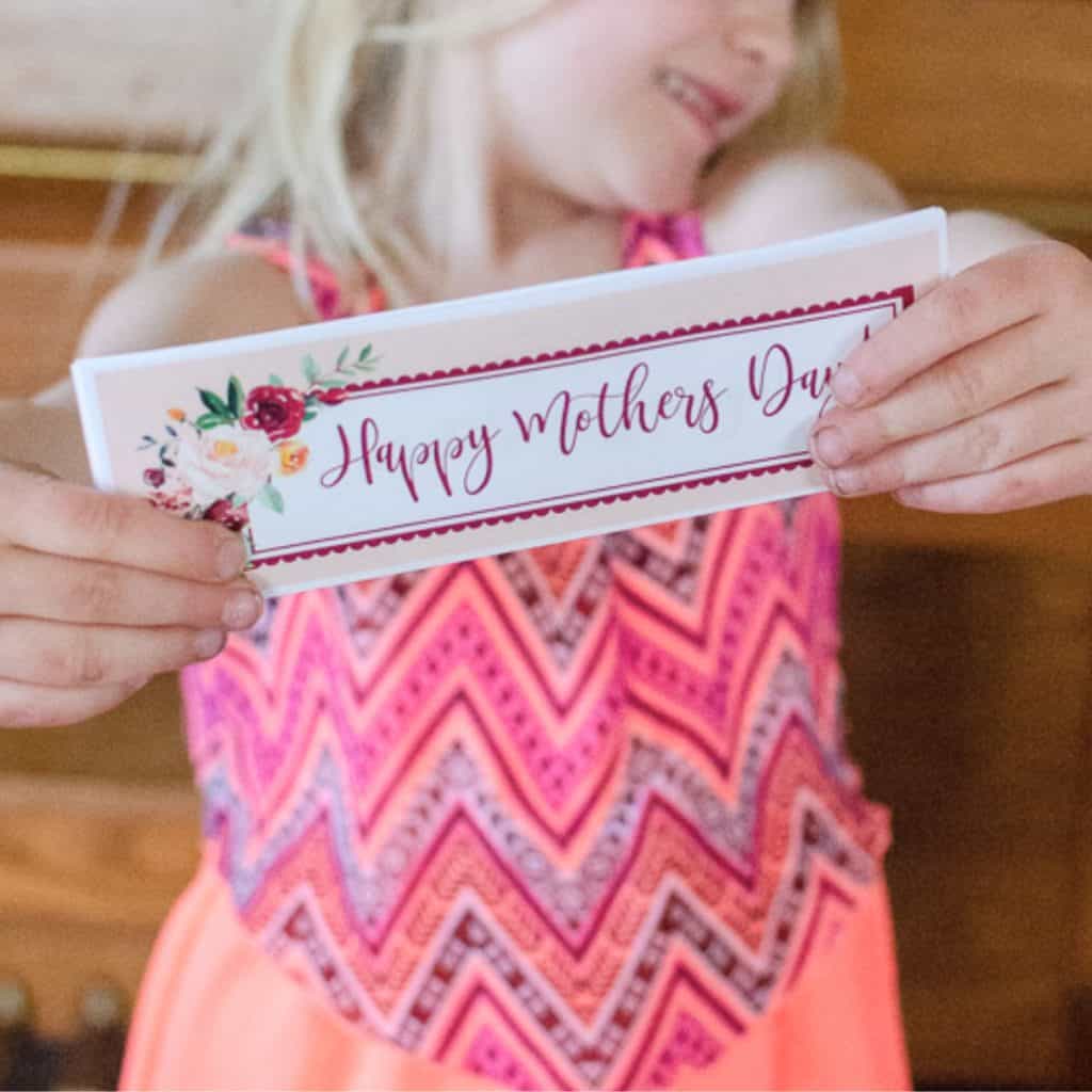 blond haired girl holds mothers day printable coupon