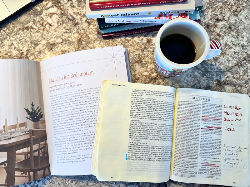 daily grace co advent book on counter with an open Bible to Matthew 1 and a cup of coffee in a christmas mug