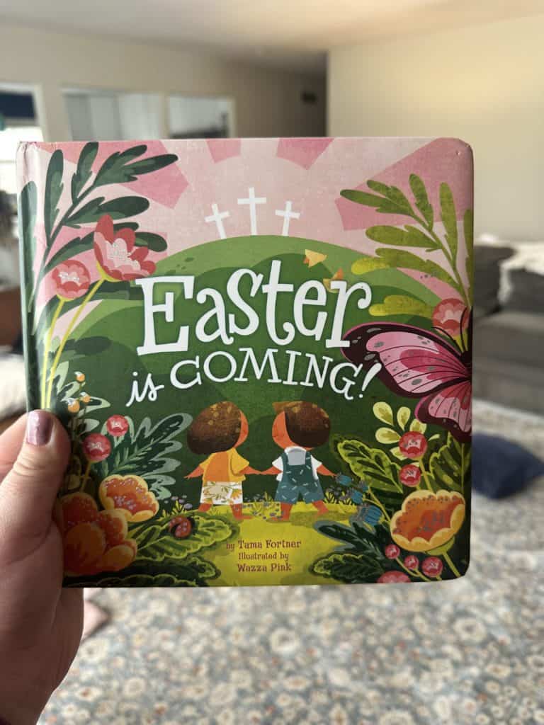 Easter is coming children's easter board book for toddler held up in a living room