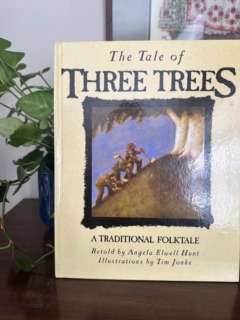 the classic Easter book The Tale of Three Trees propped on a bookshelf with a plant beside it.