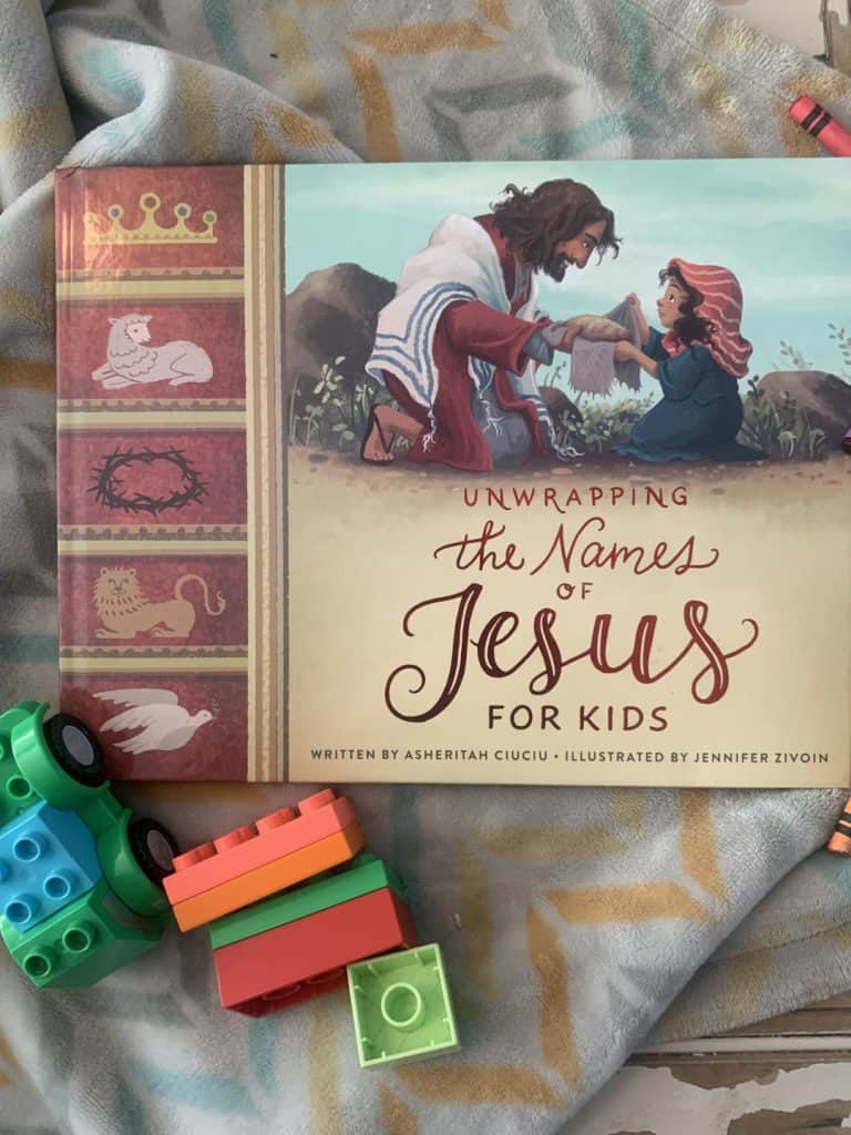 unwrapping the names of Jesus book on a soft children's blankie with duplo legos scattered around it