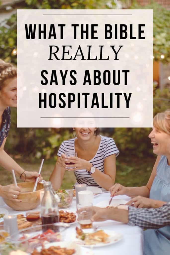 Three women gather around an outdoor table with smiles on their faces, toasting with lemonade. text overlay reads: what the bible really says about hospitality